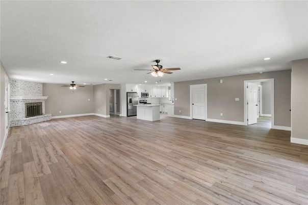 Empty room, Fireplace, Interior, Kitchen, Recessed Lighting, Stainless Steel Appliances, Wood Texture Flooring