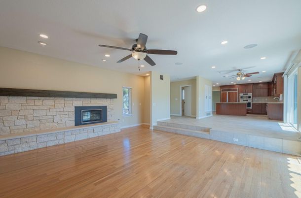 Empty room, Fireplace, Interior, Kitchen, Recessed Lighting, Stainless Steel Appliances, Stone Walls, Wood Texture Flooring