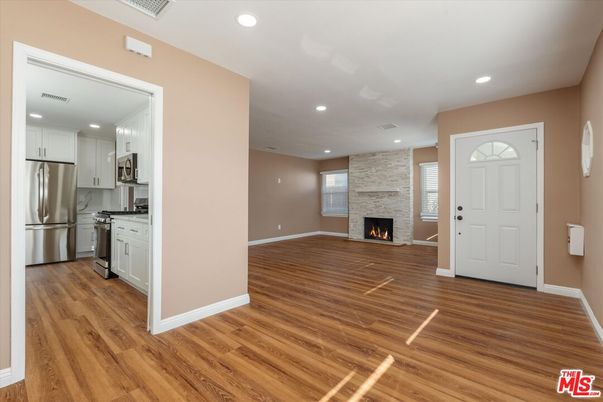 Empty room, Fireplace, Interior, Kitchen, Recessed Lighting, Stainless Steel Appliances, Wood Texture Flooring