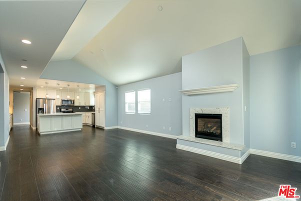 Empty room, Fireplace, Interior, Kitchen, Pendant Lights, Recessed Lighting, Stainless Steel Appliances, Wood Texture Flooring