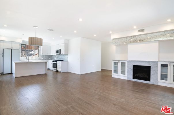 Empty room, Fireplace, Interior, Kitchen, Pendant Lights, Recessed Lighting, Stainless Steel Appliances, Wood Texture Flooring