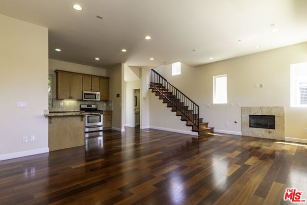 Empty room, Fireplace, Interior, Kitchen, Recessed Lighting, Stainless Steel Appliances, Wood Texture Flooring
