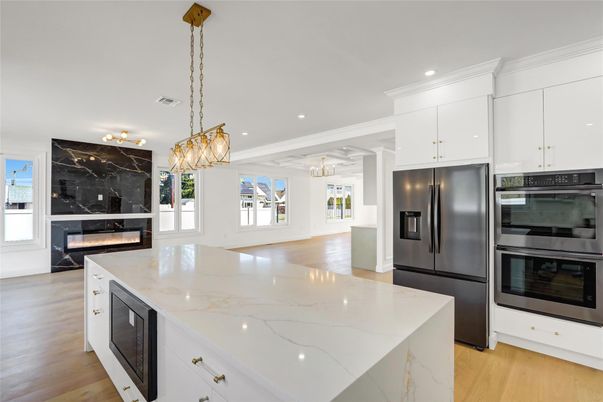 Chandelier, Fireplace, Interior, Kitchen, Marble Walls, Pendant Lights, Recessed Lighting, Stainless Steel Appliances, Wood Texture Flooring