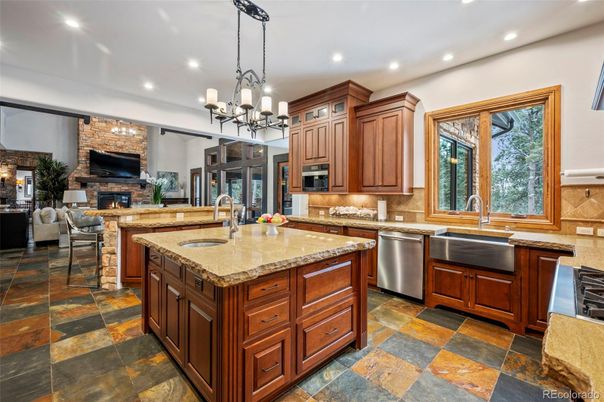 Chandelier, Fireplace, Interior, Kitchen, Living room, Pendant Lights, Recessed Lighting, Stainless Steel Appliances, Stone Walls