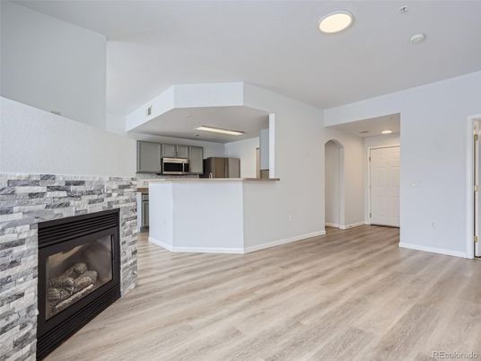 Empty room, Fireplace, Interior, Kitchen, Recessed Lighting, Stainless Steel Appliances, Wood Texture Flooring