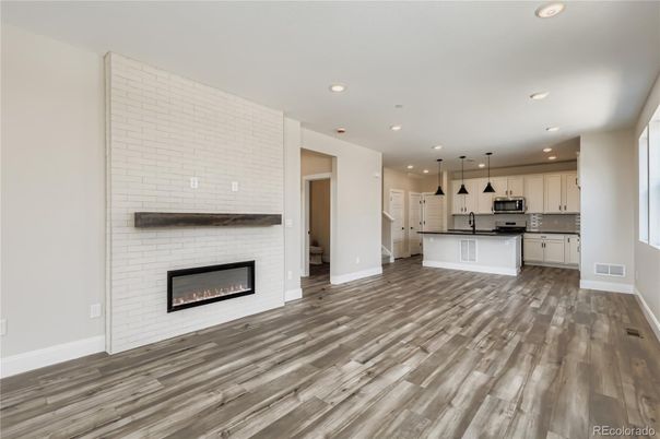 Empty room, Fireplace, Interior, Kitchen, Pendant Lights, Recessed Lighting, Stainless Steel Appliances, Wood Texture Flooring