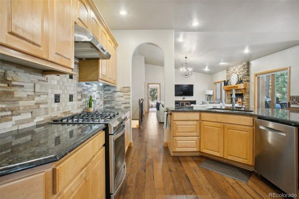 Chandelier, Fireplace, Interior, Kitchen, Recessed Lighting, Stainless Steel Appliances, Stone Walls, Wood Texture Flooring