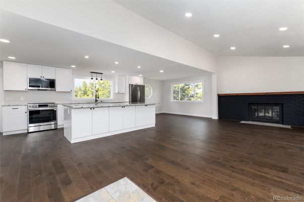 Empty room, Fireplace, Interior, Kitchen, Recessed Lighting, Stainless Steel Appliances, Wood Texture Flooring