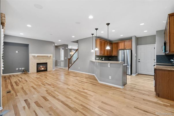 Empty room, Fireplace, Interior, Kitchen, Pendant Lights, Recessed Lighting, Stainless Steel Appliances, Wood Texture Flooring