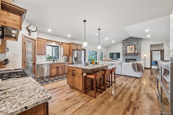 Fireplace, Interior, Kitchen, Living room, Pendant Lights, Recessed Lighting, Stainless Steel Appliances, Stone Walls, Wood Texture Flooring