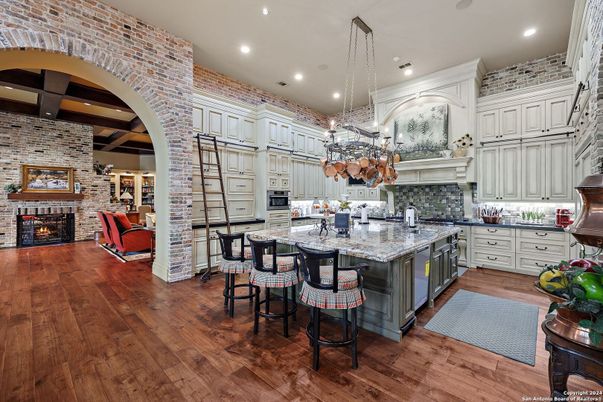 Chandelier, Fireplace, Interior, Kitchen, Living room, Recessed Lighting, Stainless Steel Appliances, Stone Walls, Wood Texture Flooring