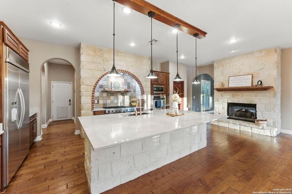 Fireplace, Interior, Kitchen, Pendant Lights, Recessed Lighting, Stainless Steel Appliances, Stone Walls, Wood Texture Flooring