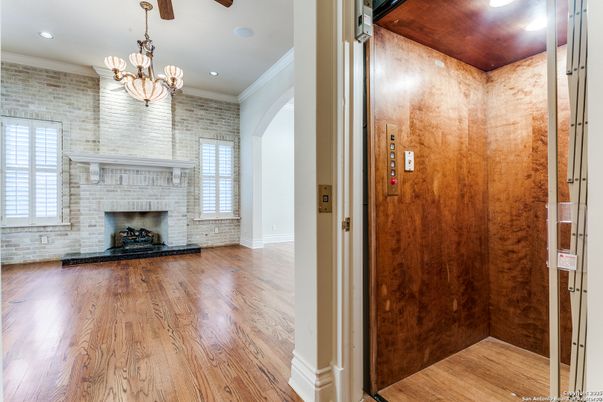 Chandelier, Elevator, Fireplace, Interior, Recessed Lighting, Stone Walls, Wood Texture Flooring