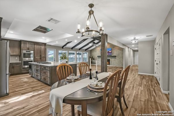 Chandelier, Dining room, Fireplace, Interior, Kitchen, Pendant Lights, Recessed Lighting, Stainless Steel Appliances, Stone Walls, Wooden Beams, Wood Texture Flooring