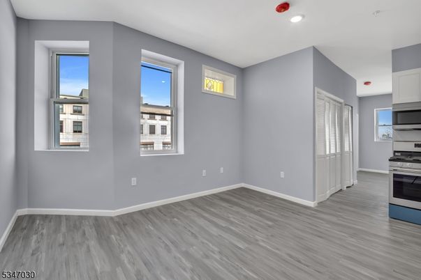 Empty room, Interior, Kitchen, Recessed Lighting, Stainless Steel Appliances, Wood Texture Flooring