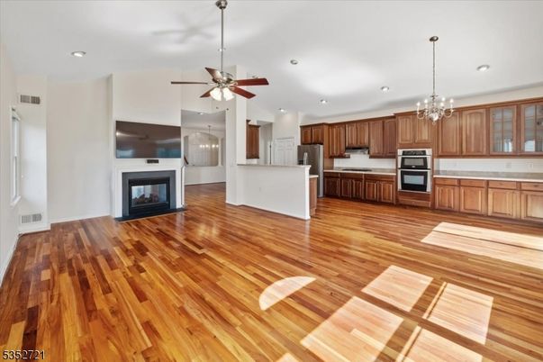Chandelier, Empty room, Fireplace, Interior, Kitchen, Pendant Lights, Recessed Lighting, Stainless Steel Appliances, Wood Texture Flooring