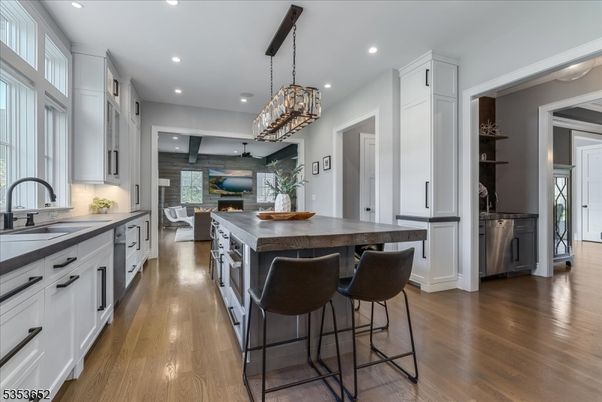 Chandelier, Dining room, Fireplace, Interior, Kitchen, Living room, Pendant Lights, Recessed Lighting, Stainless Steel Appliances, Stone Walls, Wood Texture Flooring