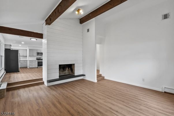 Empty room, Fireplace, Interior, Kitchen, Recessed Lighting, Stainless Steel Appliances, Wooden Beams, Wood Texture Flooring