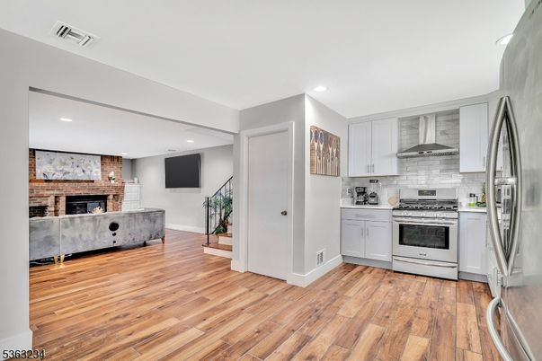 Fireplace, Interior, Kitchen, Recessed Lighting, Stainless Steel Appliances, Stone Walls, Wood Texture Flooring