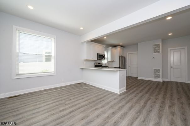 Empty room, Interior, Kitchen, Recessed Lighting, Stainless Steel Appliances, Wood Texture Flooring