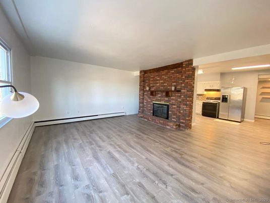 Empty room, Fireplace, Interior, Kitchen, Recessed Lighting, Stainless Steel Appliances, Stone Walls, Wood Texture Flooring