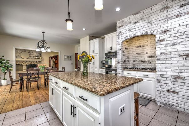 Chandelier, Dining room, Fireplace, Interior, Kitchen, Pendant Lights, Recessed Lighting, Stainless Steel Appliances, Stone Walls, Wood Texture Flooring