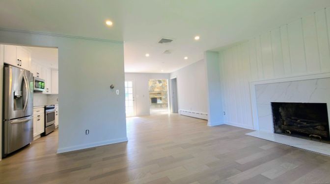 Empty room, Fireplace, Interior, Kitchen, Recessed Lighting, Stainless Steel Appliances, Wood Texture Flooring