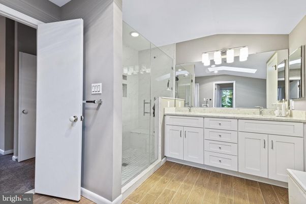 Bathroom, Dual Sink Vanities, Glass Shower, Interior, Marble Walls, Recessed Lighting, Wood Texture Flooring