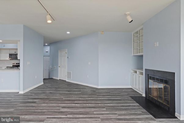 Empty room, Fireplace, Interior, Kitchen, Recessed Lighting, Stainless Steel Appliances, Wood Texture Flooring
