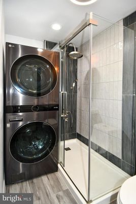 Bathroom, Glass Shower, Interior, Recessed Lighting, Washer, Wood Texture Flooring