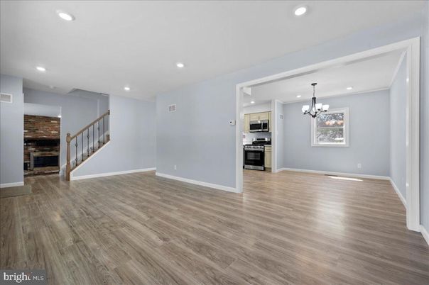 Chandelier, Empty room, Fireplace, Interior, Kitchen, Recessed Lighting, Stainless Steel Appliances, Stone Walls, Wood Texture Flooring