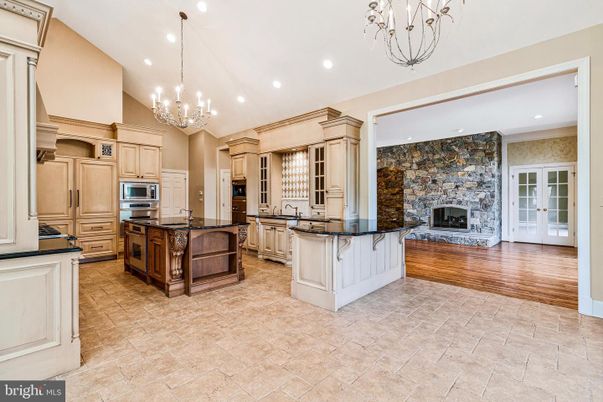 Chandelier, Fireplace, Interior, Kitchen, Recessed Lighting, Stainless Steel Appliances, Stone Walls, Wood Texture Flooring