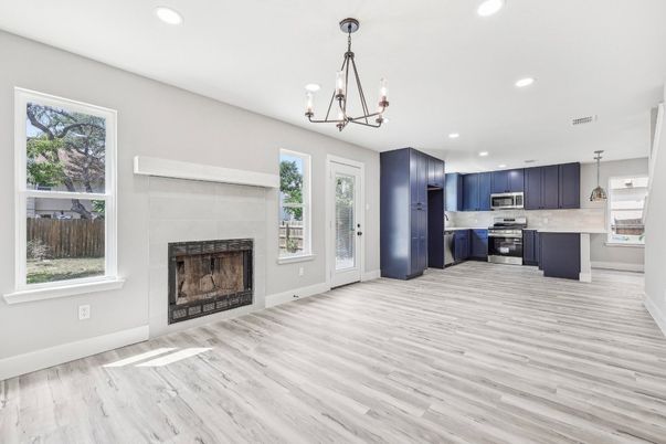 Chandelier, Empty room, Fireplace, Interior, Kitchen, Pendant Lights, Recessed Lighting, Stainless Steel Appliances, Wood Texture Flooring