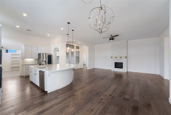 Chandelier, Empty room, Fireplace, Interior, Kitchen, Pendant Lights, Recessed Lighting, Stainless Steel Appliances, Wood Texture Flooring