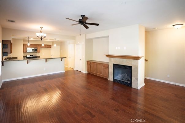 Chandelier, Empty room, Fireplace, Interior, Kitchen, Pendant Lights, Stainless Steel Appliances, Wood Texture Flooring