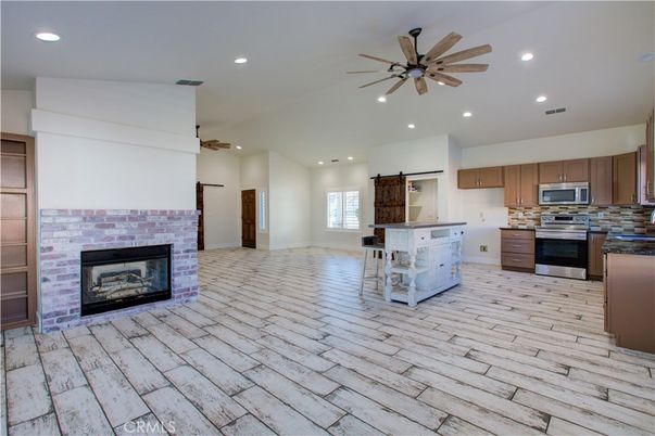 Empty room, Fireplace, Interior, Kitchen, Recessed Lighting, Stainless Steel Appliances, Wood Texture Flooring