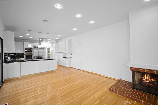 Empty room, Fireplace, Interior, Kitchen, Pendant Lights, Recessed Lighting, Stainless Steel Appliances, Wood Texture Flooring