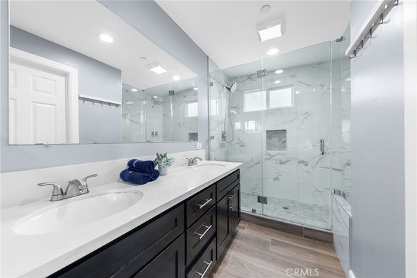 Bathroom, Dual Sink Vanities, Glass Shower, Interior, Marble Walls, Recessed Lighting, Wood Texture Flooring