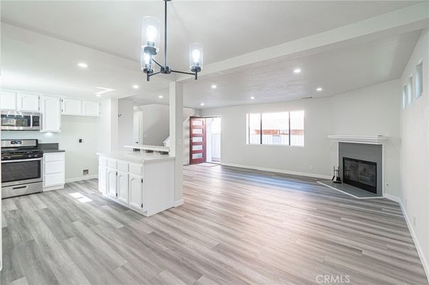 Empty room, Fireplace, Interior, Kitchen, Pendant Lights, Recessed Lighting, Stainless Steel Appliances, Wood Texture Flooring