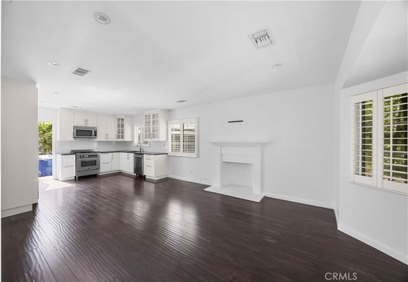 Empty room, Fireplace, Interior, Kitchen, Recessed Lighting, Stainless Steel Appliances, Wood Texture Flooring