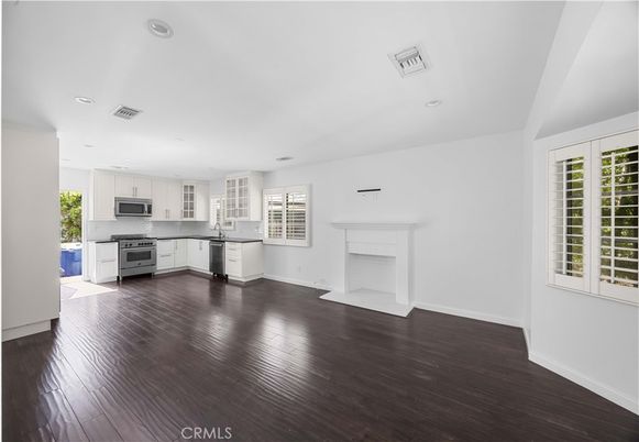 Empty room, Fireplace, Interior, Kitchen, Recessed Lighting, Stainless Steel Appliances, Wood Texture Flooring