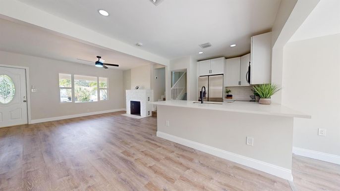 Empty room, Fireplace, Interior, Kitchen, Recessed Lighting, Stainless Steel Appliances, Wood Texture Flooring