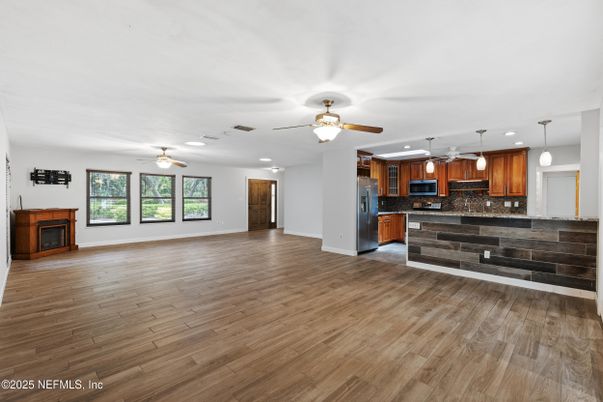 Empty room, Fireplace, Interior, Kitchen, Pendant Lights, Recessed Lighting, Stainless Steel Appliances, Wood Texture Flooring