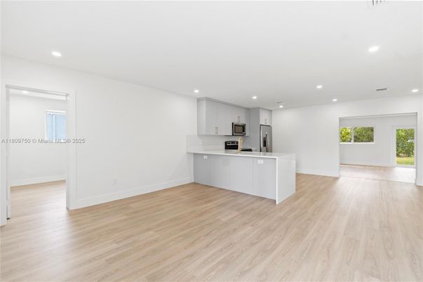 Empty room, Interior, Kitchen, Recessed Lighting, Stainless Steel Appliances, Wood Texture Flooring