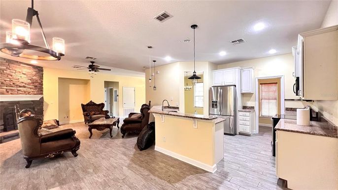 Fireplace, Interior, Kitchen, Living room, Pendant Lights, Recessed Lighting, Stainless Steel Appliances, Stone Walls, Wood Texture Flooring