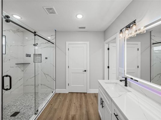 Bathroom, Dual Sink Vanities, Glass Shower, Interior, Marble Walls, Recessed Lighting, Wood Texture Flooring