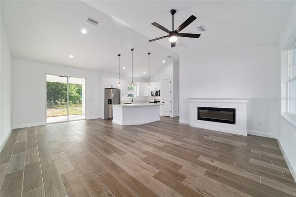 Empty room, Fireplace, Interior, Kitchen, Pendant Lights, Recessed Lighting, Stainless Steel Appliances, Wood Texture Flooring