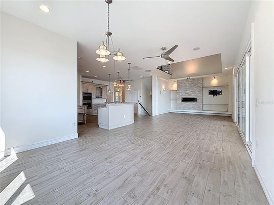 Empty room, Fireplace, Interior, Kitchen, Pendant Lights, Recessed Lighting, Stainless Steel Appliances, Wood Texture Flooring
