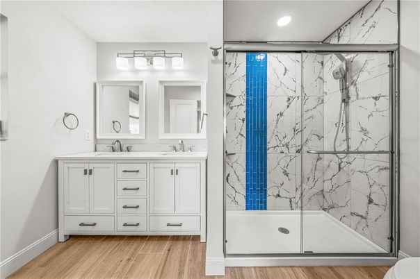 Bathroom, Dual Sink Vanities, Glass Shower, Interior, Marble Walls, Recessed Lighting, Wood Texture Flooring