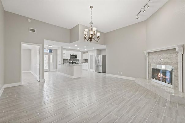 Chandelier, Empty room, Fireplace, Interior, Kitchen, Recessed Lighting, Stainless Steel Appliances, Wood Texture Flooring